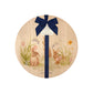 Round wooden board with rabbit and flower design, tied with a blue ribbon and gift tag.