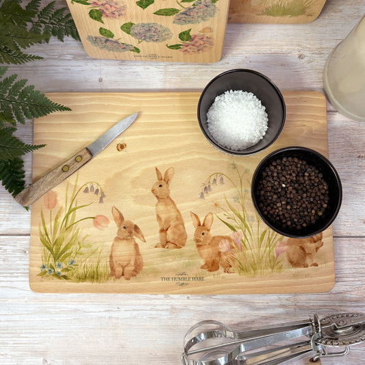 Rectangle wooden chopping board on a kitchen worktop. The beech wood board features our blooming bunnies woodland animal design, with rabbits among spring flowers.