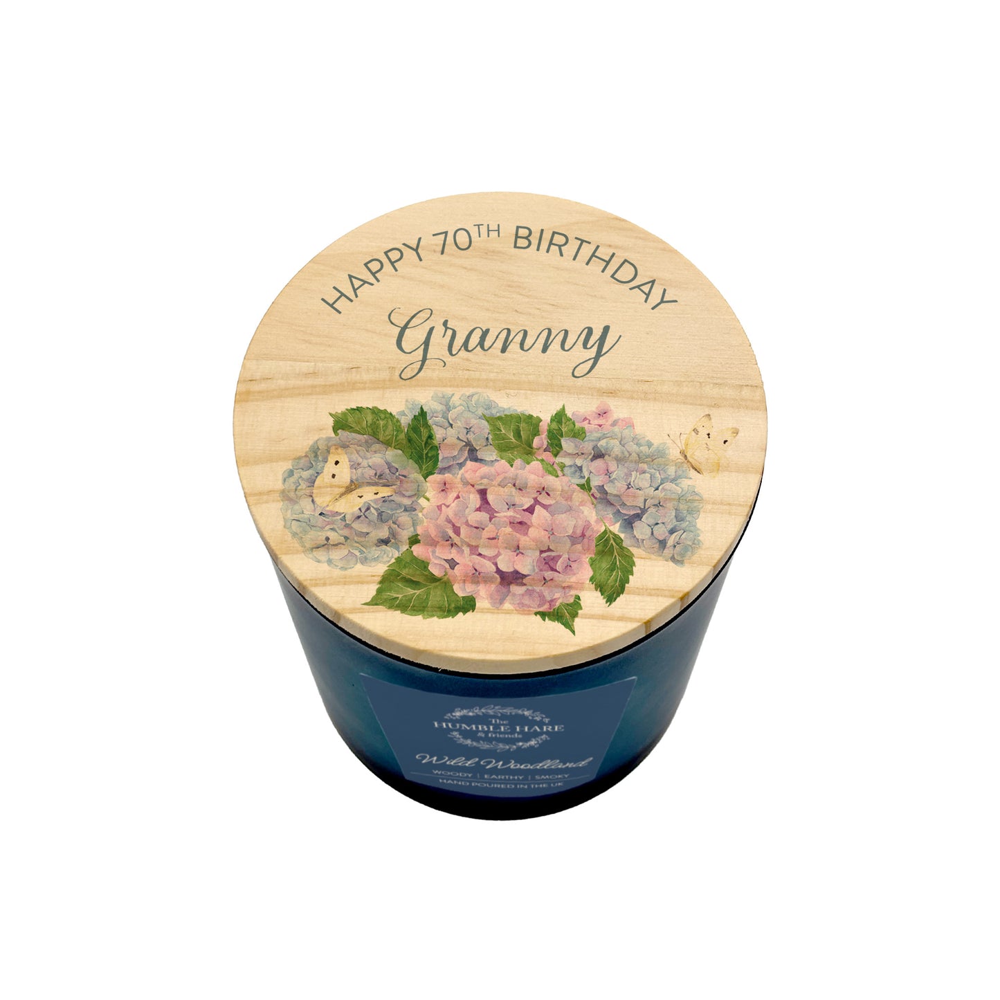 A birthday candle in a dark blue glass jar with a light wood lid  personalised with 'HAPPY 70TH BIRTHDAY Granny' and decorated with pink and blue hydrangeas.