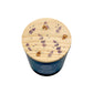 A dark blue glass jar candle with a round light wood lid decorated with lavender and bumblebees, shown on a plain white background.