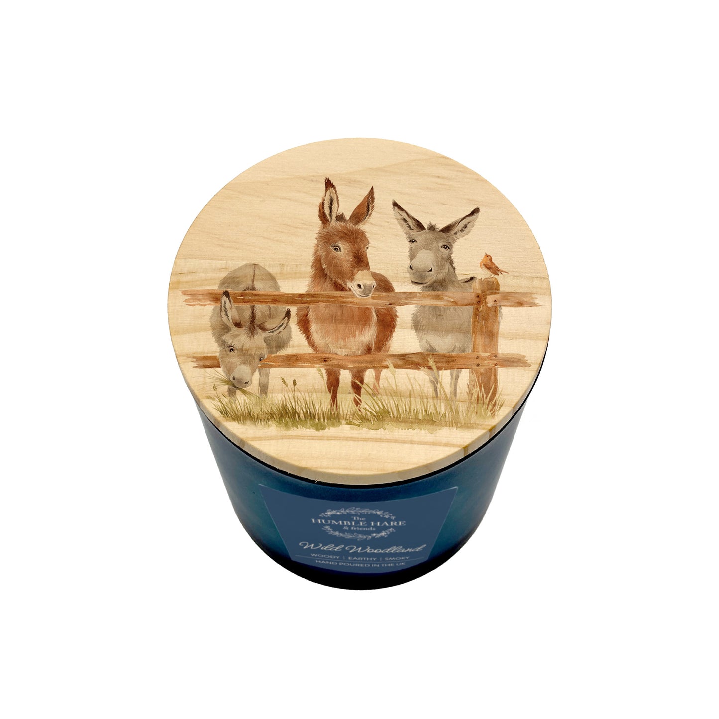 A blue glass jar candle with a round wooden lid featuring an illustration of three donkeys and a robin.