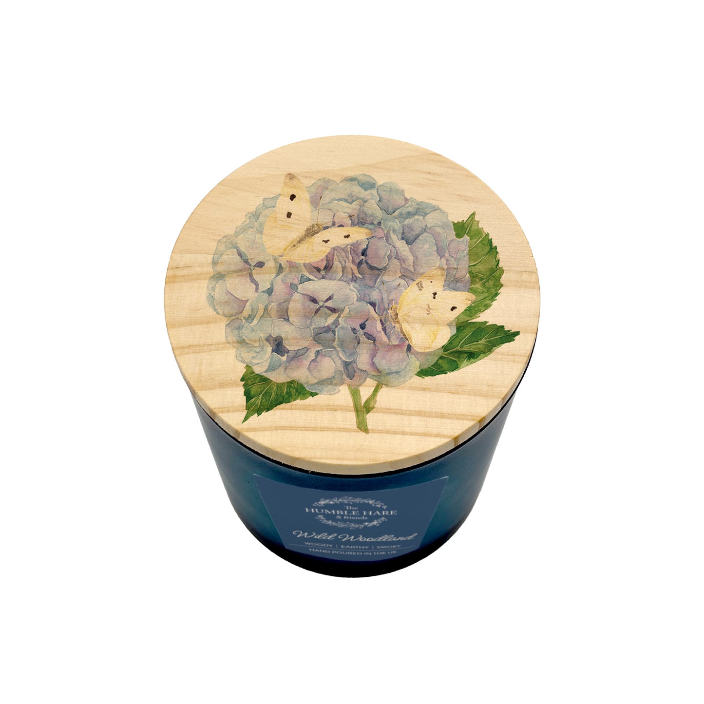 A soy wax candle in a dark blue glass jar with a round light wood lid decorated with a hydrangea and butterfly design, shown on a white background.