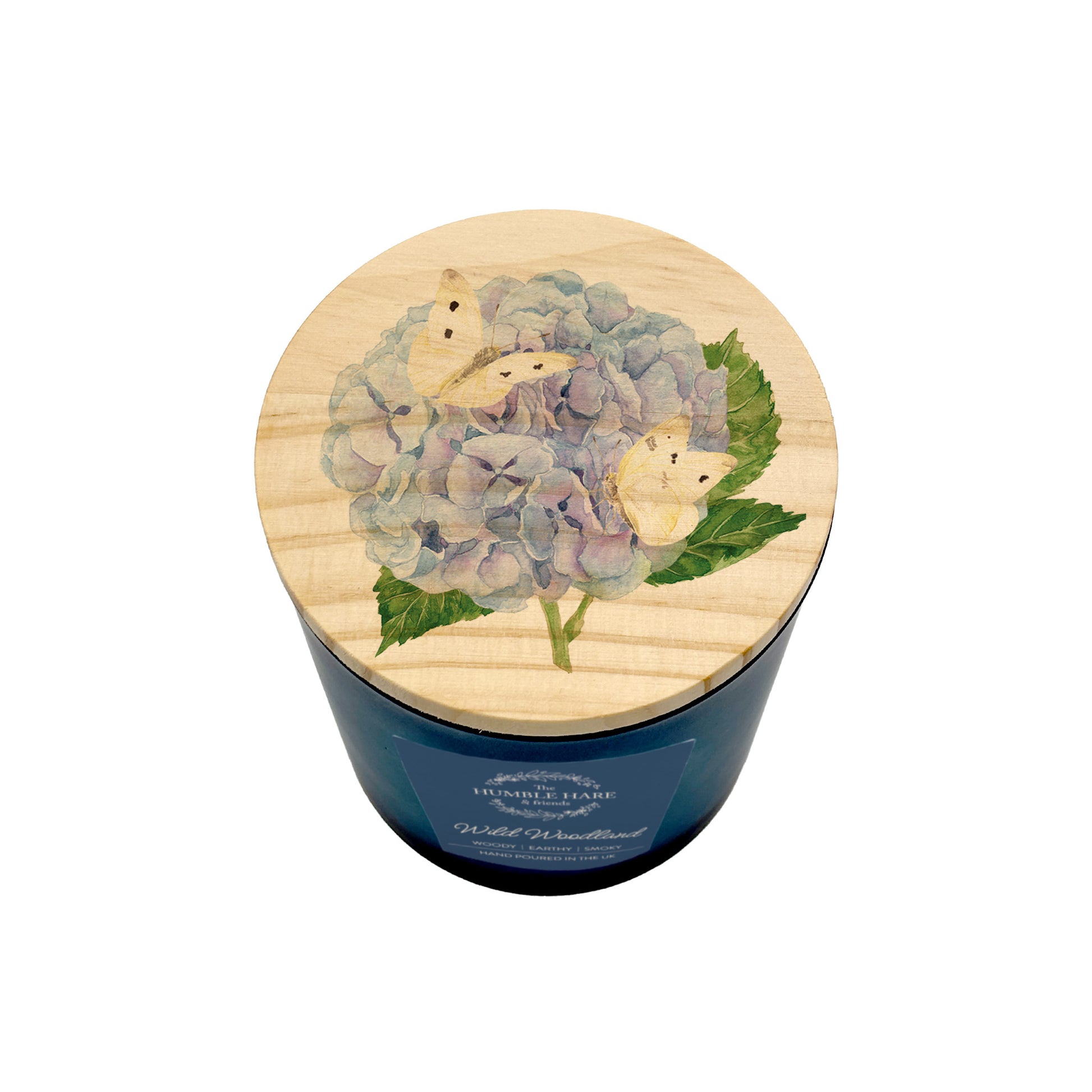 A soy wax candle in a dark blue glass jar with a round light wood lid decorated with a hydrangea and butterfly design, shown on a white background.