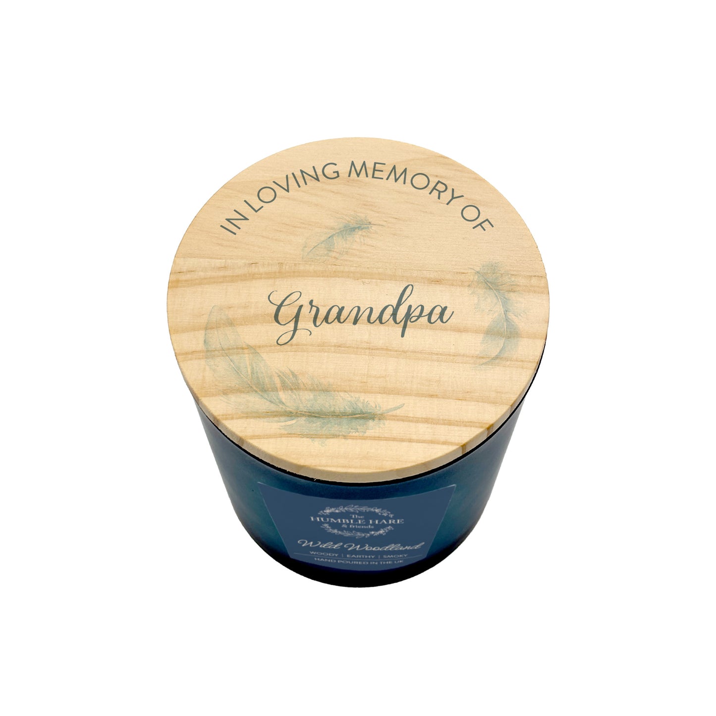 A personalised memorial candle in a dark blue glass jar with a round light wood lid illustrated with feathers and with the text 'IN LOVING MEMORY OF Grandpa'.