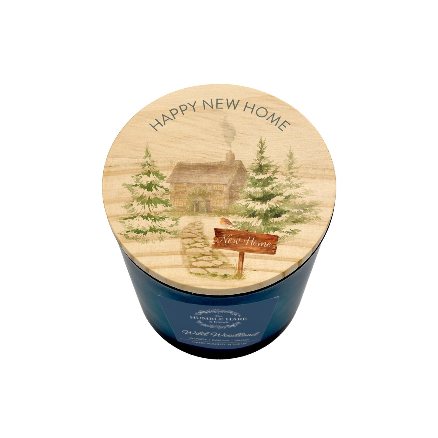 A blue glass jar candle with a round wooden lid printed with a winter cabin scene and the words 'HAPPY NEW HOME' and 'New Home'.
