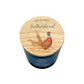 A personalized scented candle in a dark blue glass jar with a round wooden lid. The lid features an illustration of a pheasant couple and the text 'MR & MRS Sutherland'.