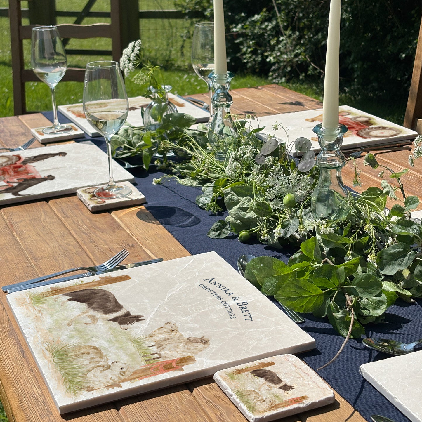 A square large marble placemat with a design of a border collie working dog herding sheep through a gate on the farm. The place mat is personalised with custom text and set on a wooden country kitchen table.