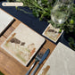 A square medium marble platter with a design of a border collie working dog herding sheep through a gate on the farm. The platter is set on a wooden country kitchen table.