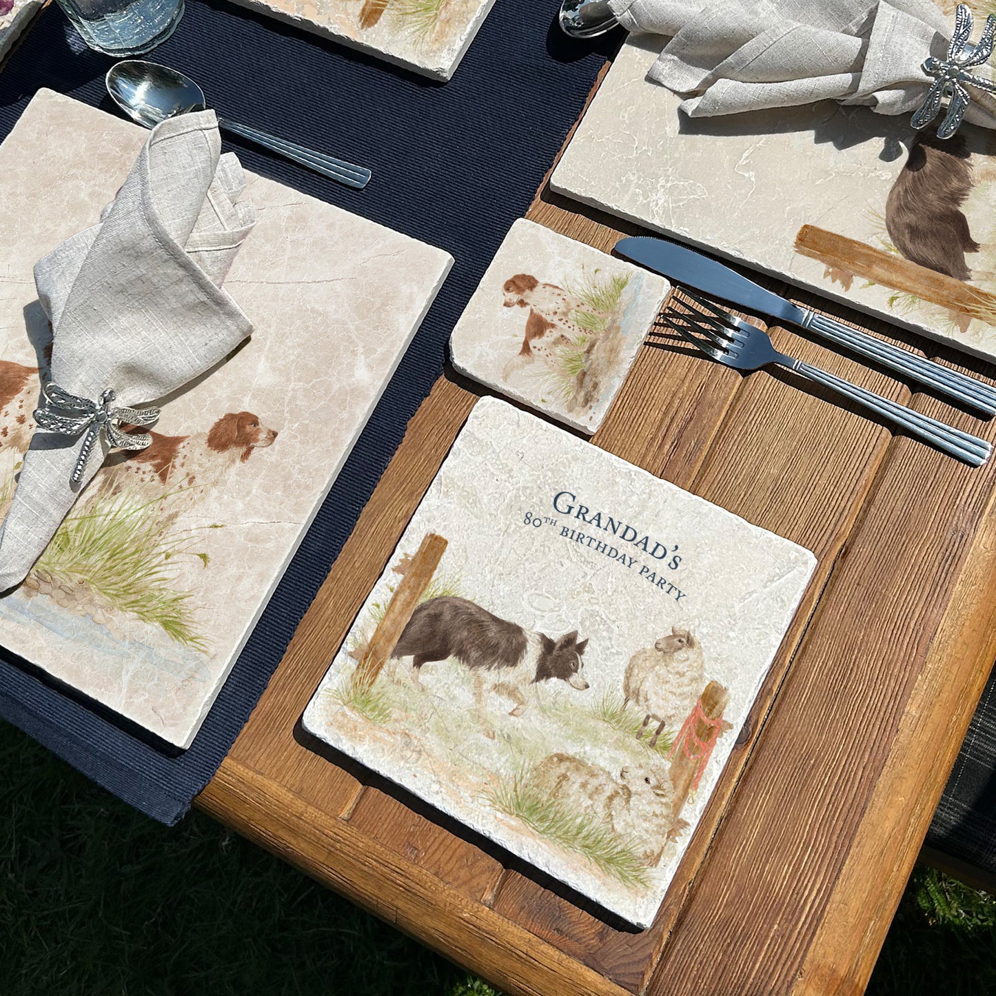 A square medium marble platter with a design of a border collie working dog herding sheep through a gate on the farm. The platter is personalised with custom text and set on a wooden country kitchen table.