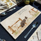 A rectangular marble sharing platter with a watercolour design of a border collie working dog herding sheep through a gate on the farm. The platter is personalised with custom text and set on a wooden country kitchen table.