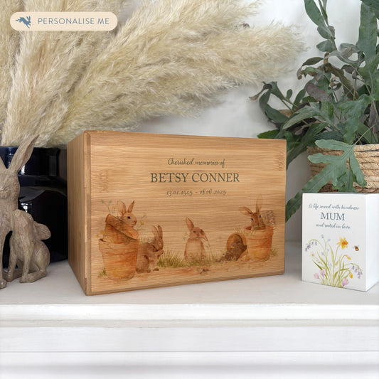 A beautifully crafted solid Bamboo wooden urn, finished with a soft watercolour design of Bunny's in pots  Thoughtfully made for either display or burial, this personalised urn can be customised to create a meaningful memorial. Perfect for holding ashes of a loved one or a beloved pet, it serves as a comforting tribute and keepsake. 