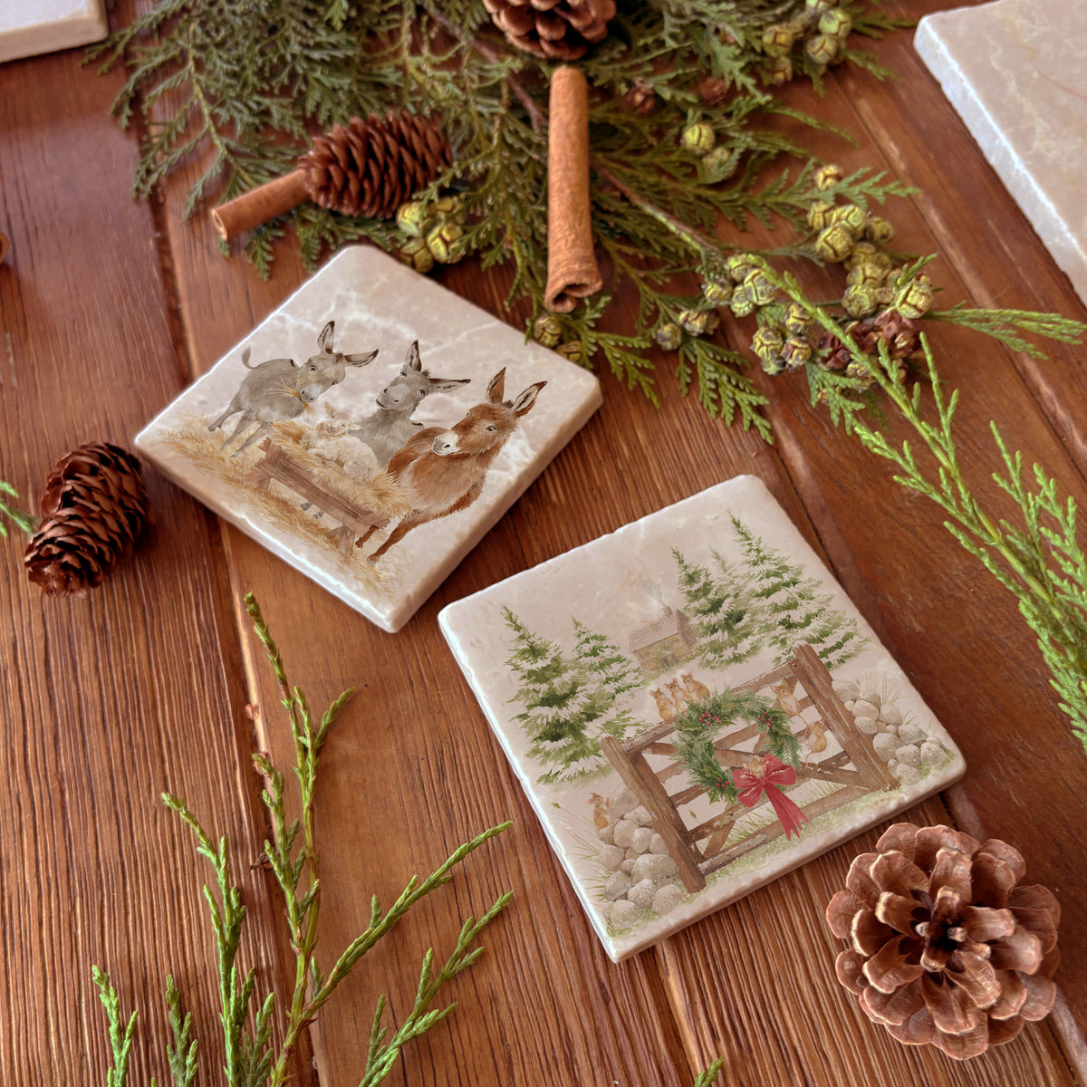 A set of mix and match marble coasters featuring different Christmas designs including a donkey nativity scene and a winter forest scene with a cottage and mice on a gate with a Christmas wreath