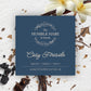 A square dark blue product label for The Humble Hare's Cosy Fireside vanilla and tobacco scented candle, styled on a white textured surface with vanilla flowers and pods.