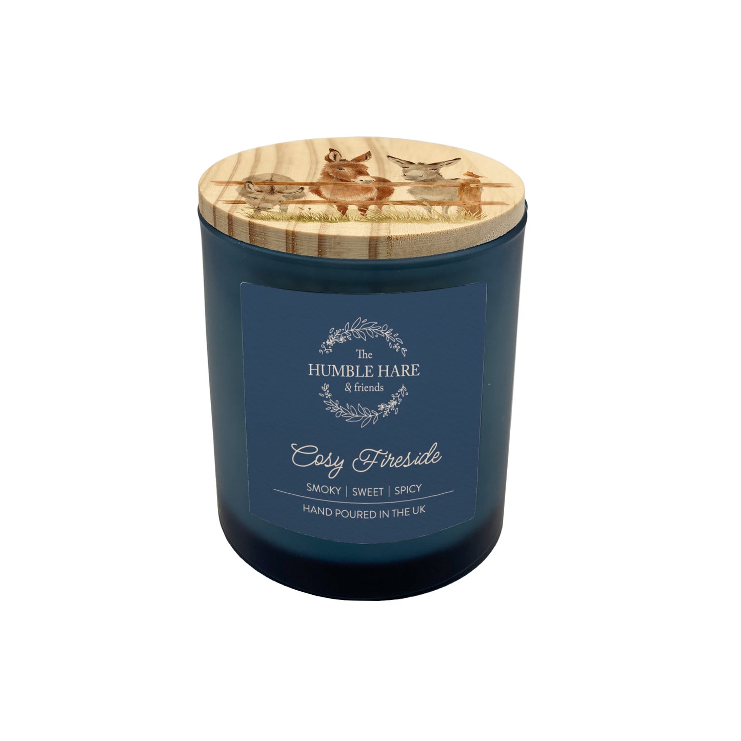 A dark blue glass jar candle with a light wood lid featuring donkeys lined up along a fence. The candle is The Humble Hare's Cosy Fireside scent, with vanilla, spices and tobacco leaf notes.
