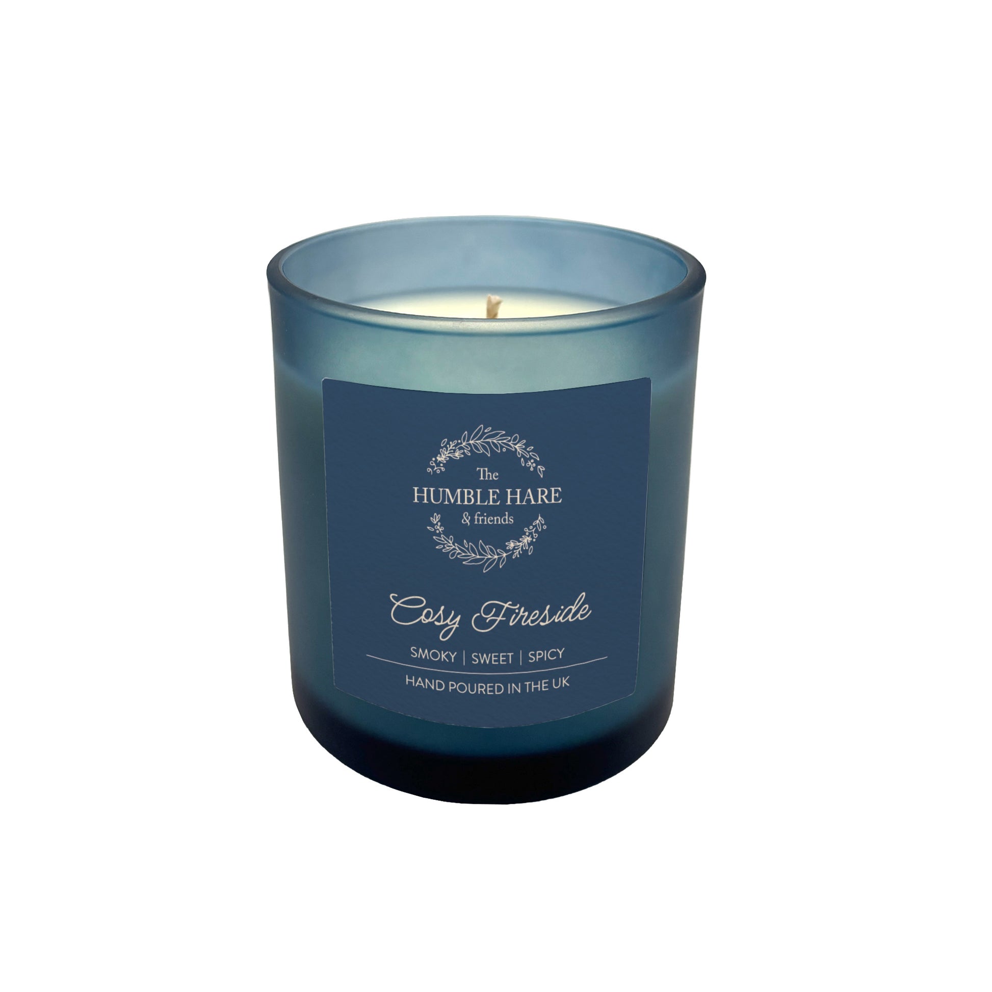 A dark blue glass jar candle in The Humble Hare's Cosy Fireside scent, with vanilla, spices and smoky tobacco leaf notes.