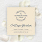 A square cream-colored label for 'The Humble Hare & friends' candle scent 'Cottage Garden', styled on a textured white background with scattered white rose petals.