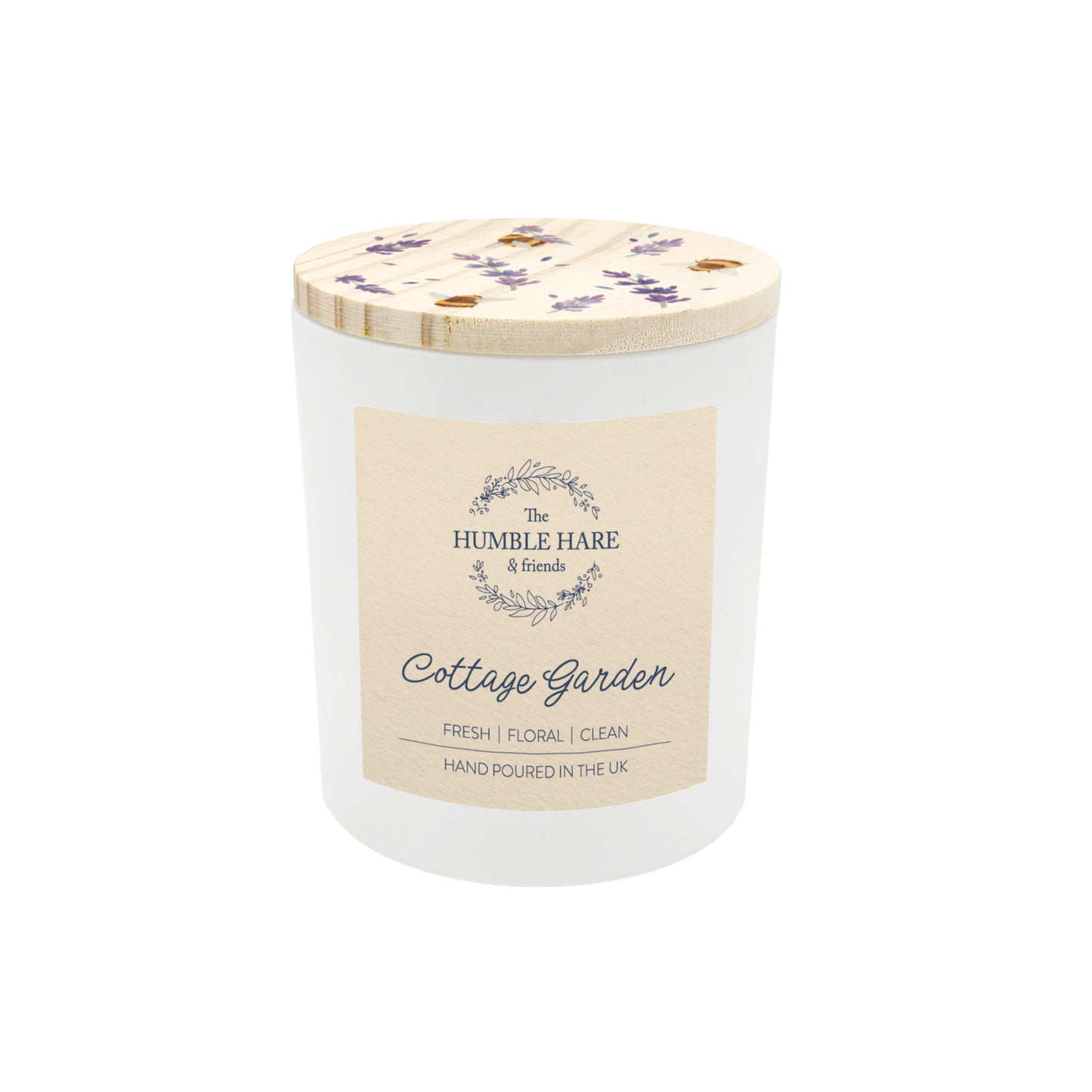 A white glass jar candle with a light wood lid decorated with lavender flowers and bees. The candle is The Humble Hare's Cottage Garden, a floral clean washing scent.