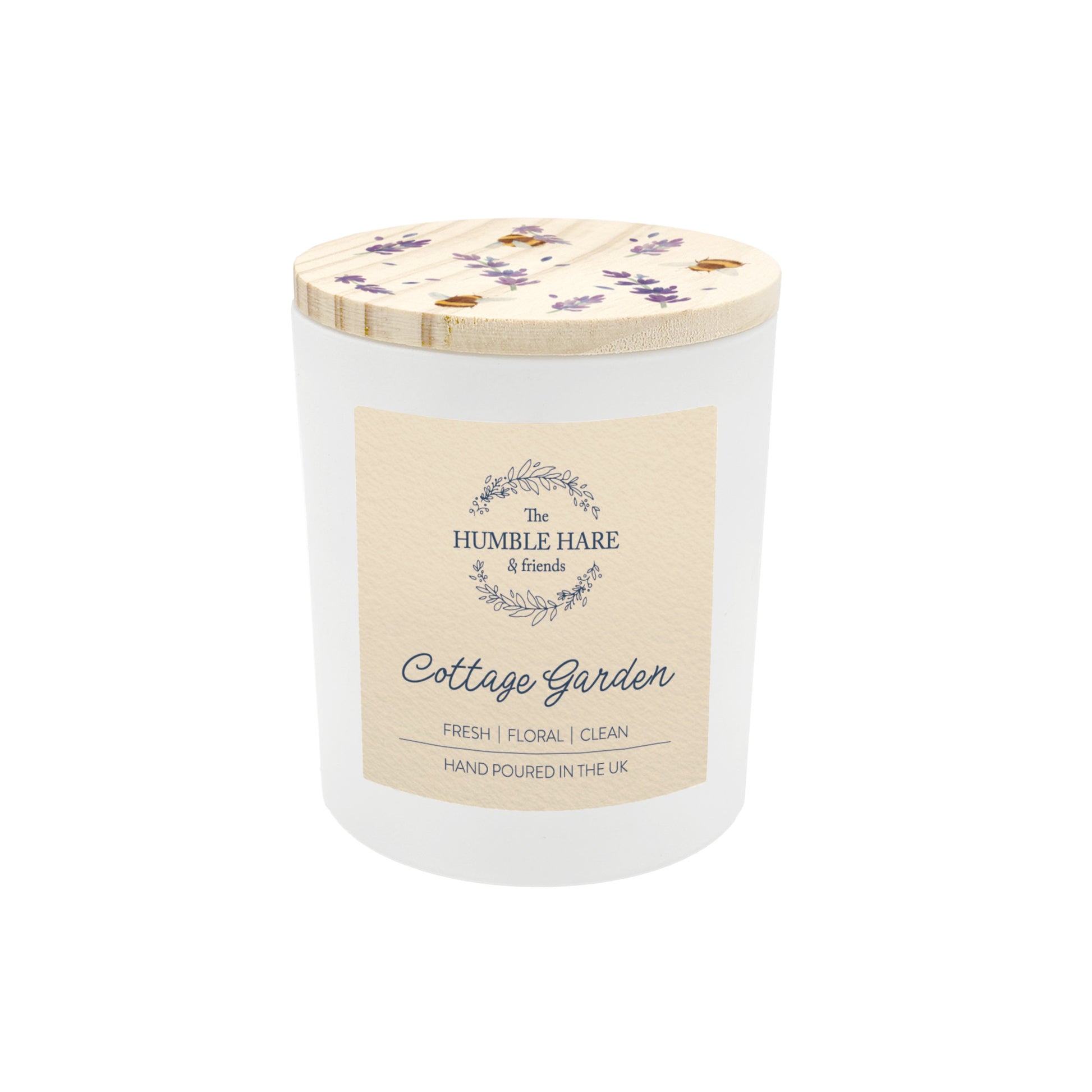 A white glass jar candle with a light wood lid decorated with lavender flowers and bees. The candle is The Humble Hare's Cottage Garden, a floral clean washing scent.