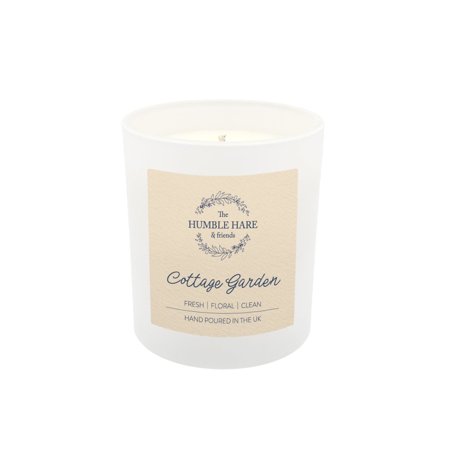 A white glass jar soy wax candle with a cream paper label. The candle is The Humble Hare's Cottage Garden, a floral clean washing scent.