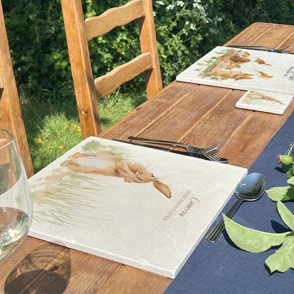 A beautiful garden table set with personalised marble placemats and coasters, ready for a dinner party. The placemats feature countryside animals with personalised names above them.