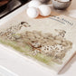 A large square marble platter featuring a  watercolour design of 3 dalmatian dogs and personalised with custom text. The platter is sat next to an aga in the kitchen.