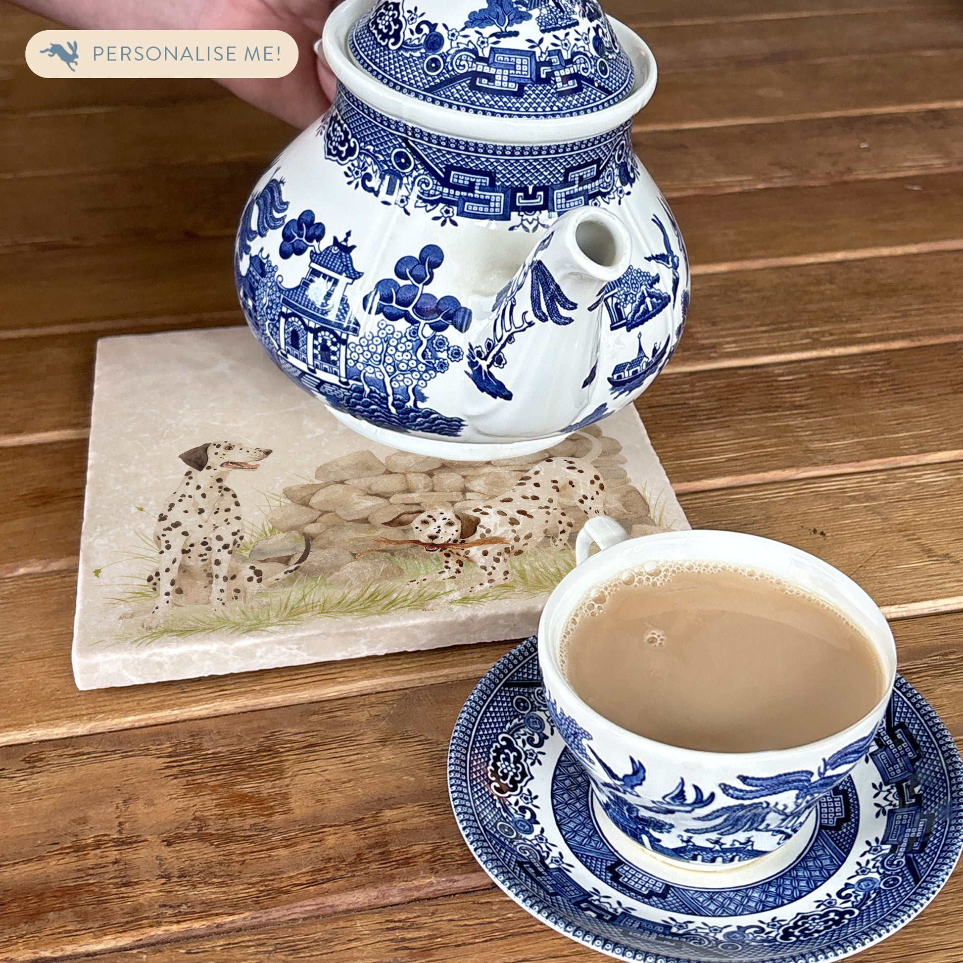 A square medium marble platter featuring a  watercolour design of 3 dalmatian dogs playing in the countryside. The platter is being used as a teapot stand.