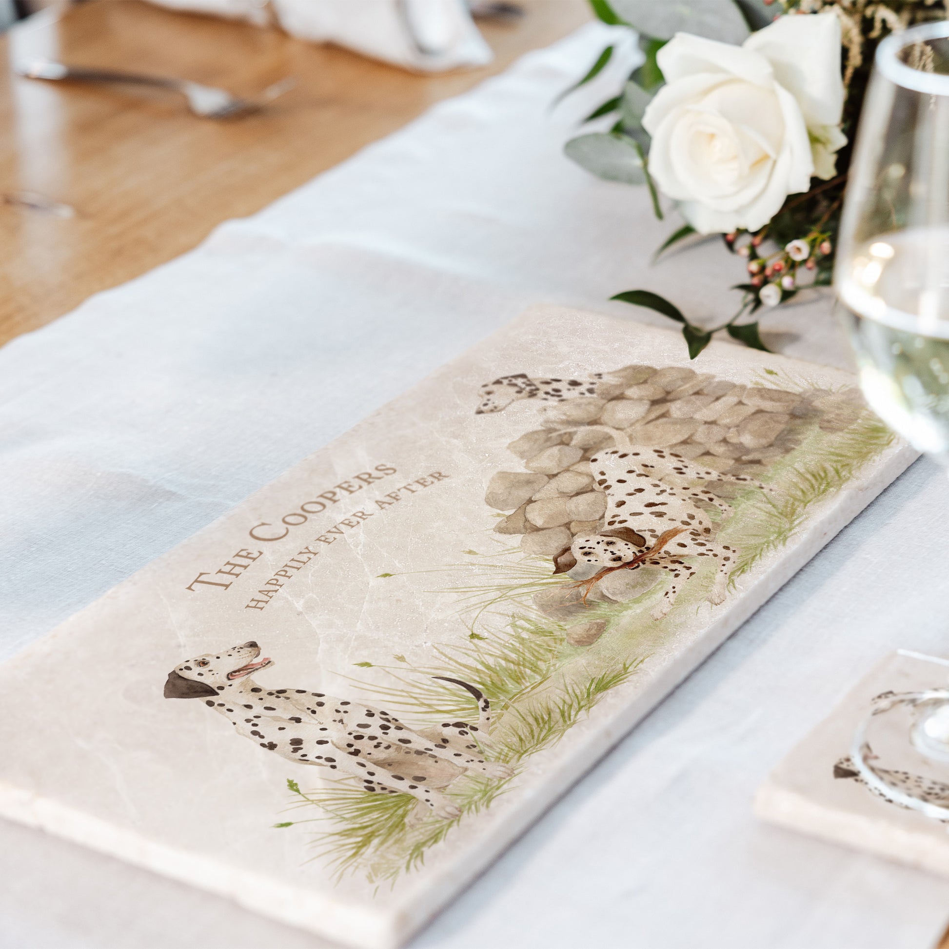 A rectangular marble sharing platter featuring a watercolour design of 3 dalmatian dogs and personalised with custom text. The platter is set on a dining table.