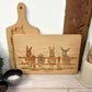 Rectangle wooden chopping board on a kitchen worktop. The beech wood board features  a watercolour design of cheeky donkeys peering over their fence.