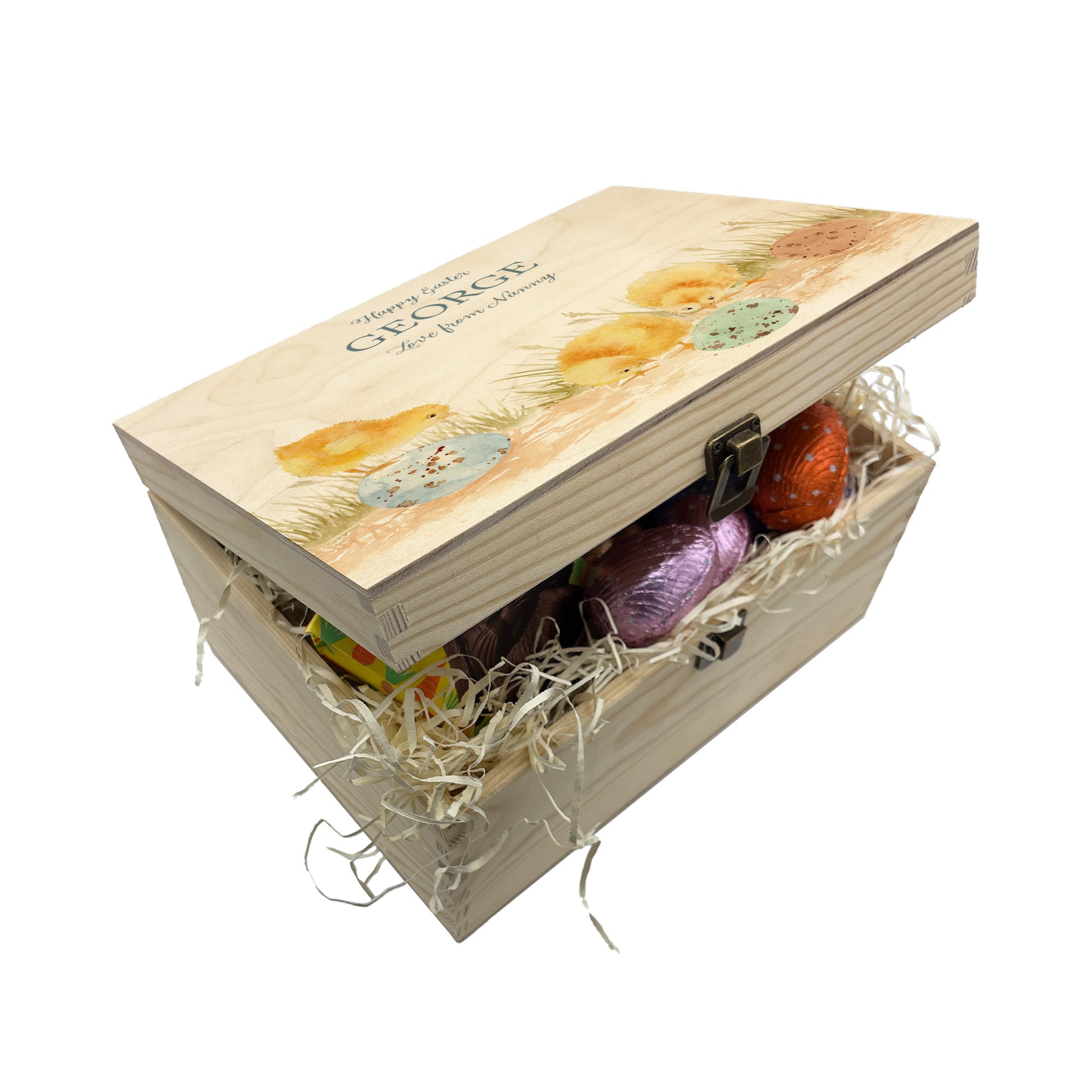 This wooden keepsake box is a large Easter box, perfect for creating a box full of Easter eggs and treats. The box is great for storing keepsakes in once the Easter treats have been eaten. This design has 3 chicks, the three chicks are looking at the pastel colour easter eggs on the floor  wondering if any more chicks may hatch or not. This gift box is full of easter chocolate treats 