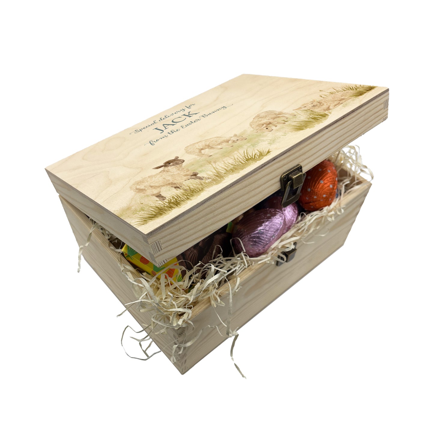 Small Easter personalised wooden pine box, perfect for Easter treats, eggs, gifting. Children gifts. This box has a beautiful easter theme of 4 Lambs grazing in the spring Meadow  This box can be personalised in 4 phrases or it can just have the design and no text. This wooden box is such a great personalised gift. This picture also shows a great example of filling your Easter box full with chocolate treats and biscuits. 