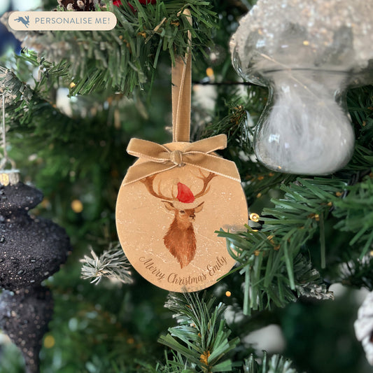 An oval marble bauble featuring a watercolour stag, personalised with your choice of text to create a Christmas decoration unique to you! The bauble is finished with a velvet ribbon.