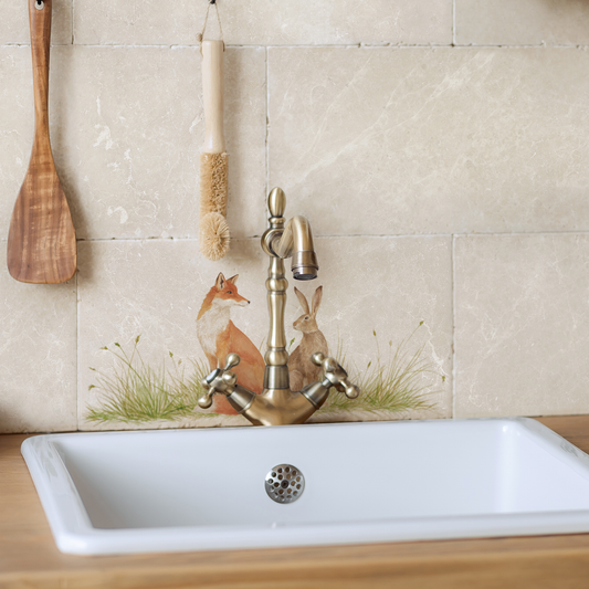 A tiled splashback behind a farmhouse kitchen sink made up of rectangular marble tiles 20x40cm, featuring a fox and hare watercolour design.