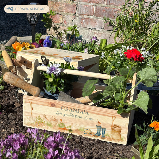 wooden luxury Trug/Caddy the perfect personalised gift. Each product is lovingly designed, handmade with our Countryside inspired watercolour designs. This design features a gardening scene with wellie boots, a sake of potatoes, vegetables, a watering con and a little robin. set in a flower bed unique designs for a truly one off special occasion for a loved one. 