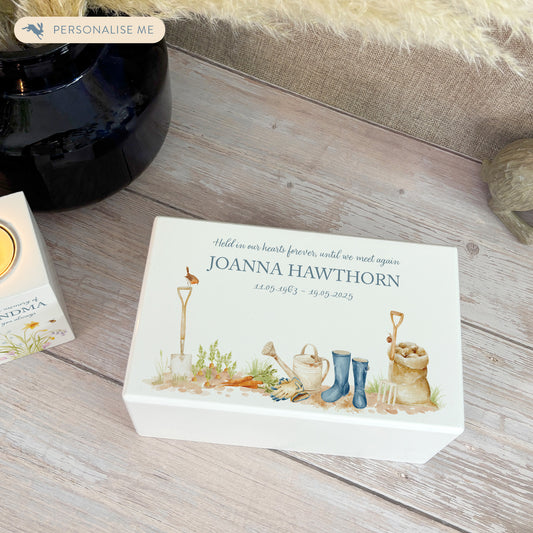 A beautifully crafted solid wooden urn, finished in white with a soft watercolour design for the avid Gardener "Gone Gardening" Thoughtfully made for either display or burial, this personalised urn can be customised to create a meaningful memorial. Perfect for holding ashes of a loved one or a beloved pet, it serves as a comforting tribute and keepsake.