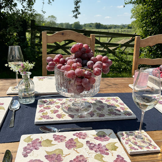 A beautiful garden tablescape set with marble platters and coasters featuring a maximalist watercolour purple grape vine pattern.