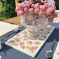 A rectangular marble sharing platter featuring a watercolour grape vine pattern. The platter is being used as the centrepiece on an outdoor table in a sunny garden.