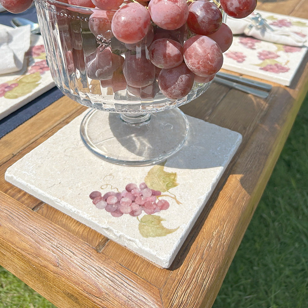 A medium cream marble platter featuring a single bunch of purple grapes.