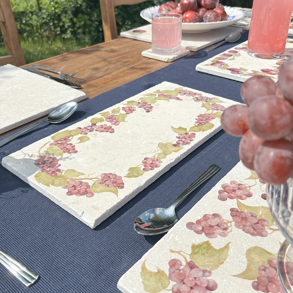 An al fresco dinner table in the garden, set with marble serving platters featuring a grape vine wreath watercolour design.