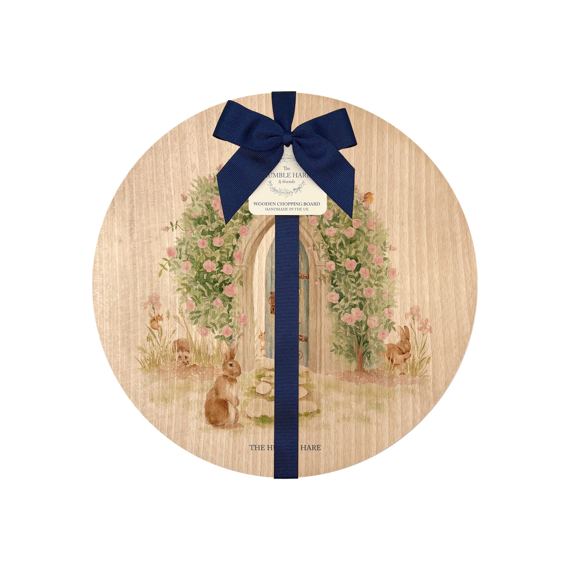 Round beech wood chopping board featuring a watercolour design of hidden garden with roses, rabbits and a hedgehog. The wooden board is finished with a blue gift ribbon and tag.