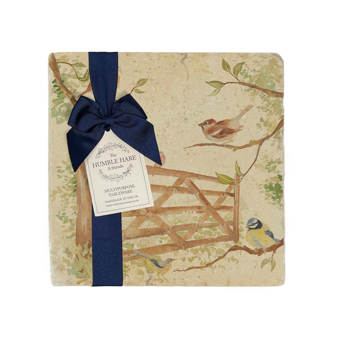 A multipurpose medium marble platter with a design featuring British garden birds in the hedgerow around the paddock gate, packaged with a luxurious dark blue bow and branded gift tag.
