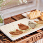 A rectangle marble sharing platter being used to serve breakfast pastries. The platter has a watercolour design featuring four hens in a farmyard.