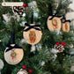 Four oval marble Christmas ornaments with blue velvet ribbon loop and bows hanging on a Christmas tree, featuring vintage-style illustrations of a robin, highland cow, sheep and donkey wearing a green wreath and red bow, with personalised text written at the bottom.