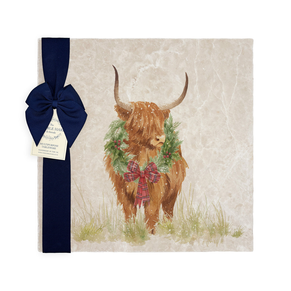 A large square marble placemat with a watercolour highland cow wearing a Christmas wreath around his neck. The platter is gift wrapped with a navy blue bow and paper tag.