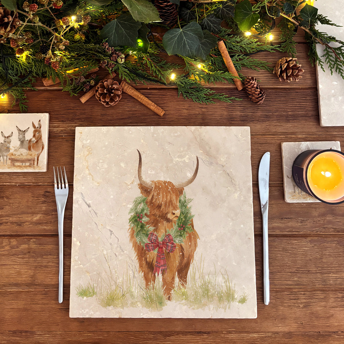 A large square marble placemat with a watercolour highland cow wearing a Christmas wreath around his neck.