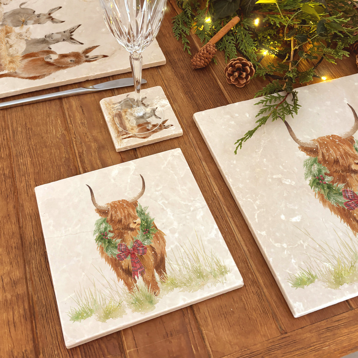 A square medium marble platter featuring a watercolour illustration of a Highland cow with a Christmas wreath around his neck.