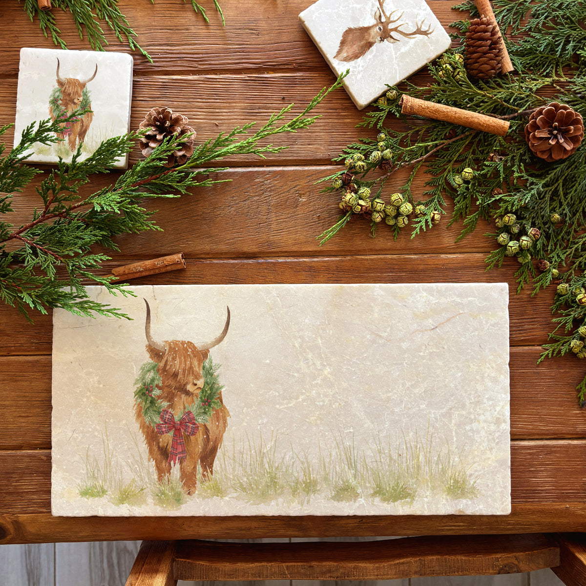 A rectangular marble sharing platter featuring a watercolour highland cow with a Christmas wreath and tartan bow around his neck.