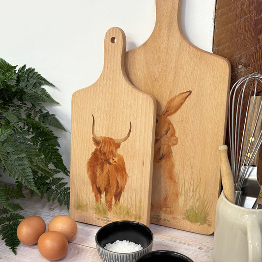 Handmade paddle board in Beech wood, featuring a water colour Highland Cow design with a hand tied luxury blue ribbon. perfect chopping board, charcuterie board, serving board and chopping board. 