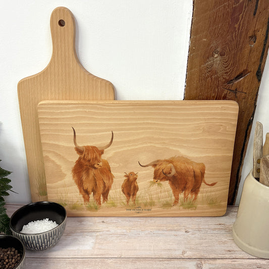 Handmade rectangular chopping board featuring a watercolour Highland Cow illustration, finished with blue ribbon.