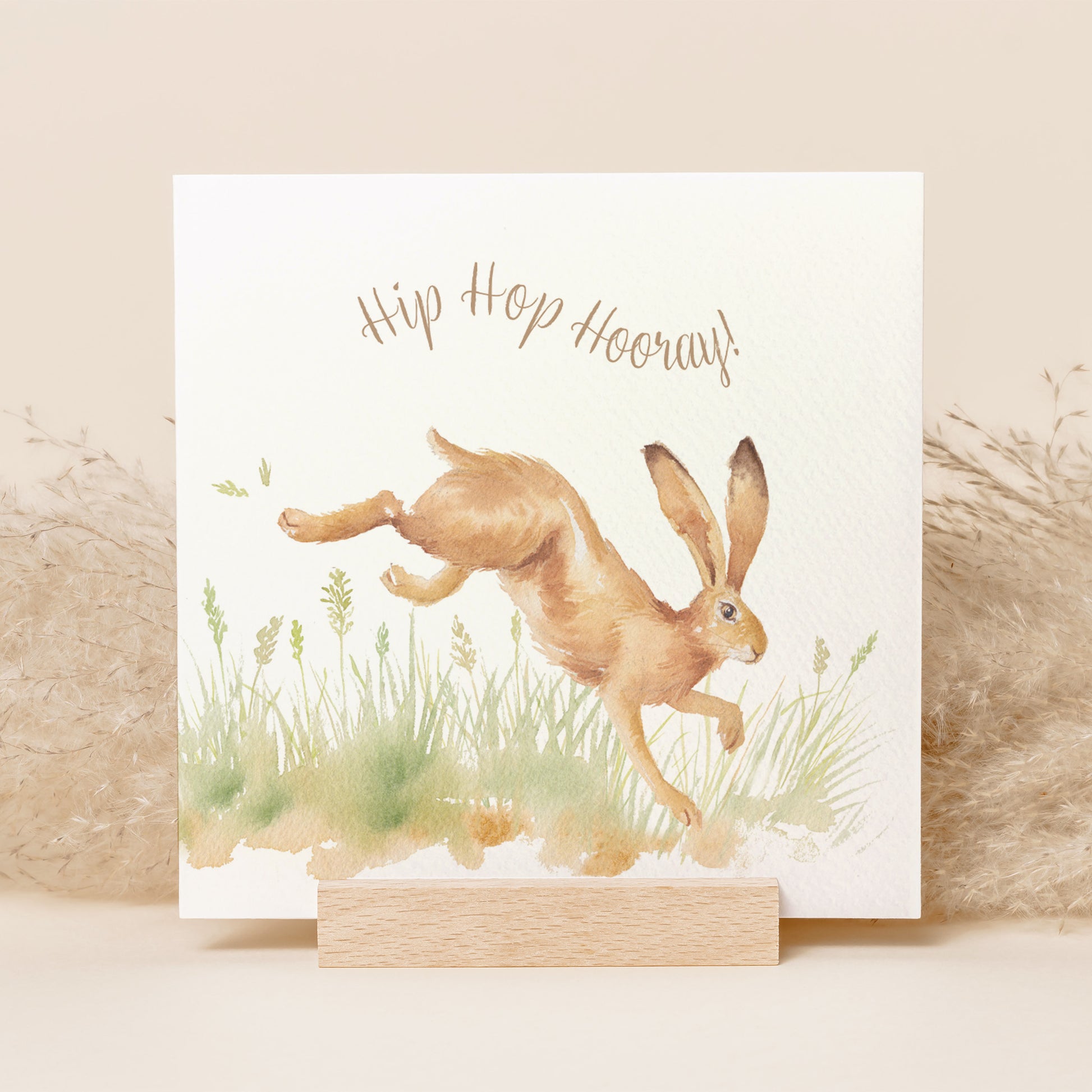 A greetings card reading Hip Hop Hooray in brown text above a leaping hare in a watercolour style.