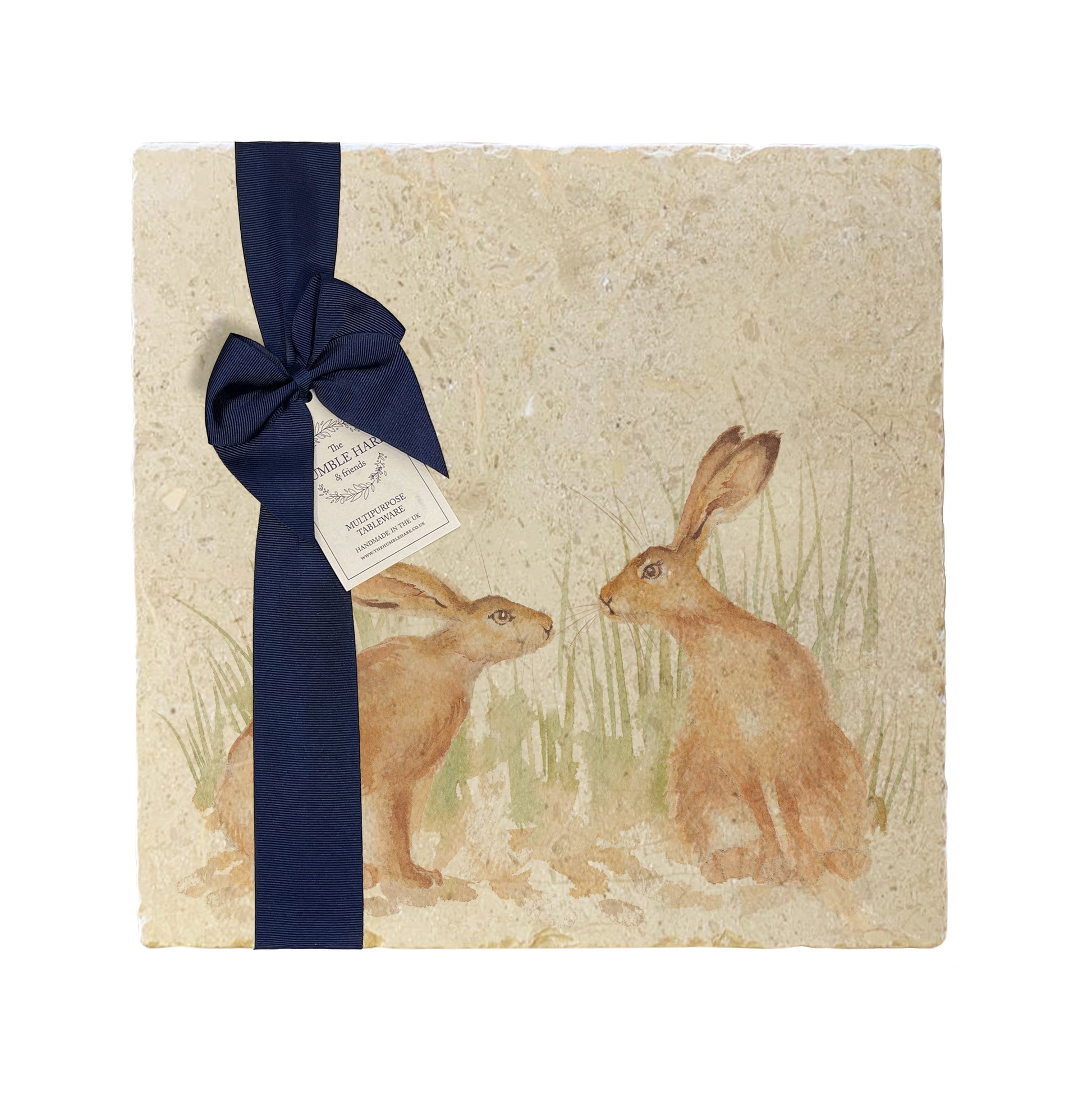 A multipurpose marble platter with a design featuring two hares facing each other about to touch noses, packaged with a luxurious dark blue bow and branded gift tag.